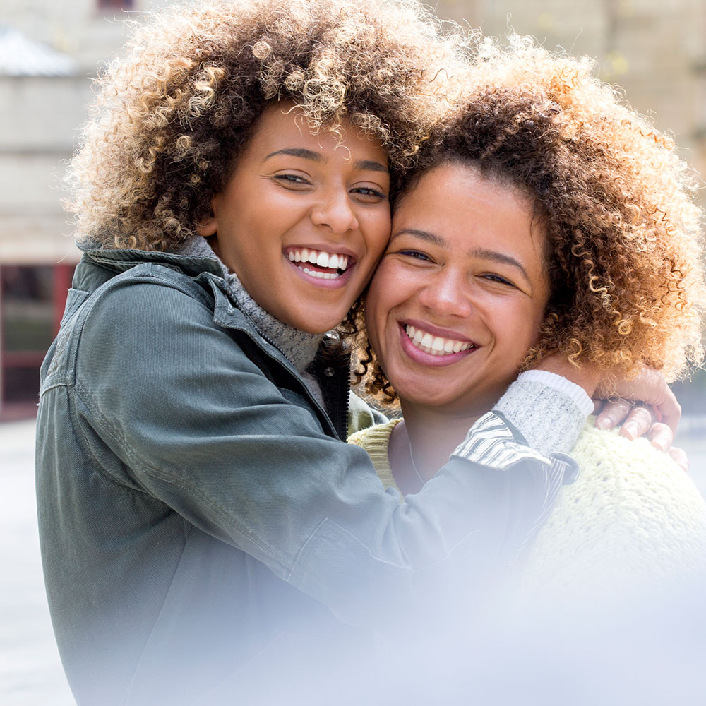 Two happy women embrace