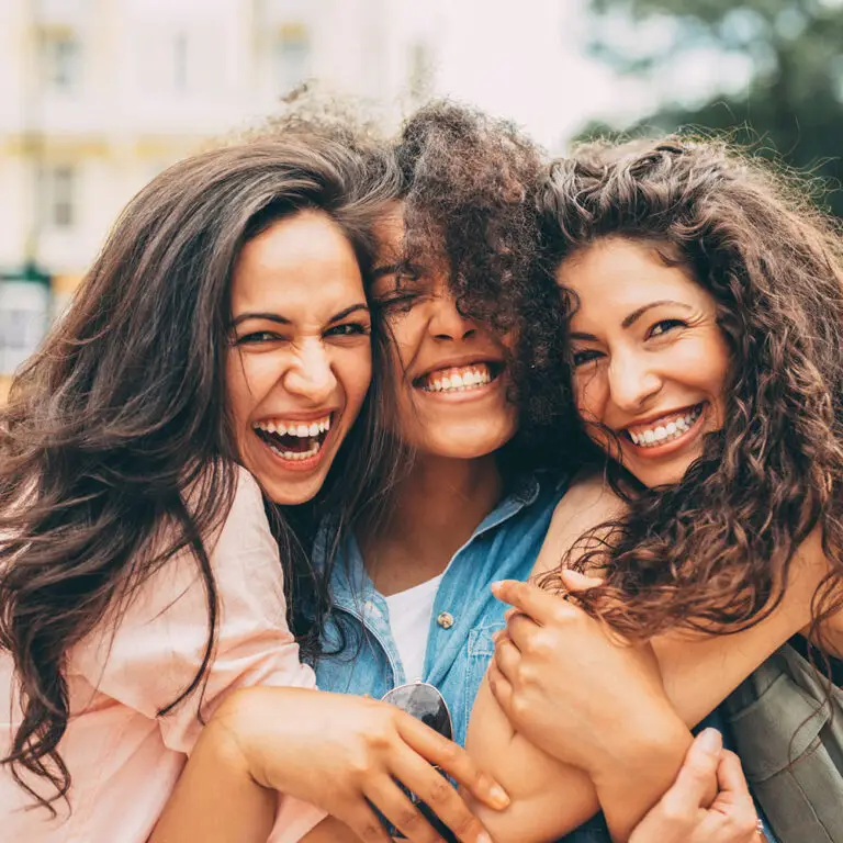 Three young multiracial friends smiling and a taking selfie.